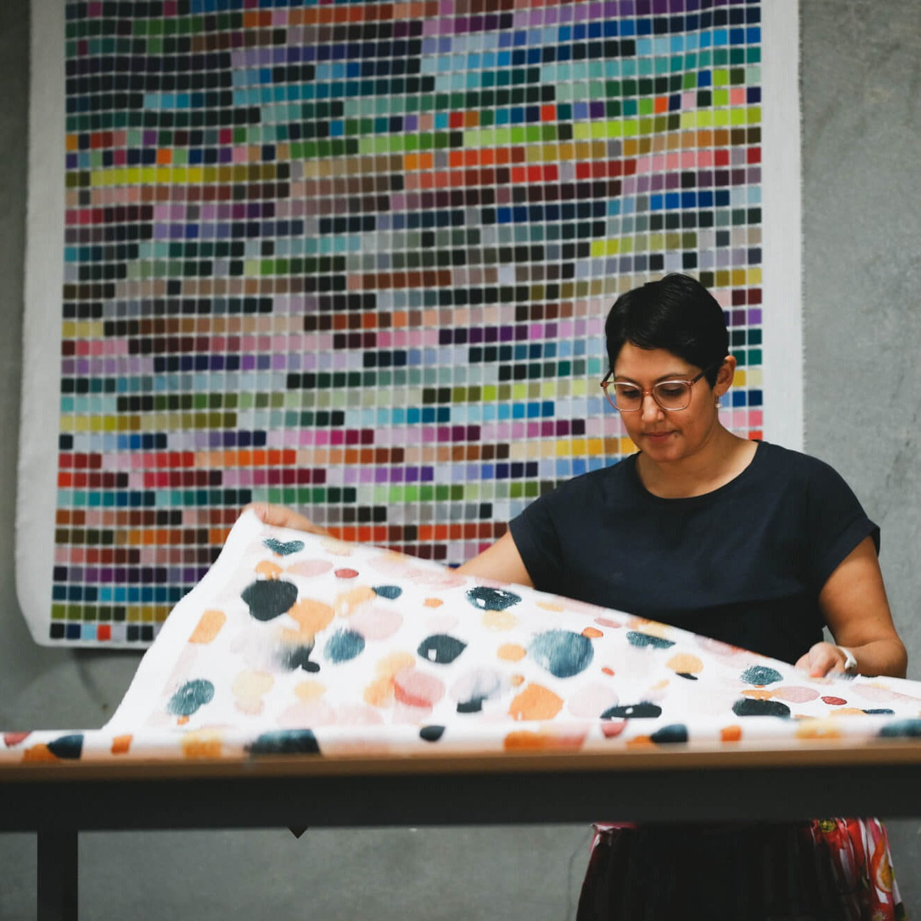 Rameez checking digital print fabric. A fabric colour chart hangs in the background.