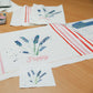 Sample artwork for DIY cushion kit. Lavendar flowers iwth the word "poppy" are printed on the front.